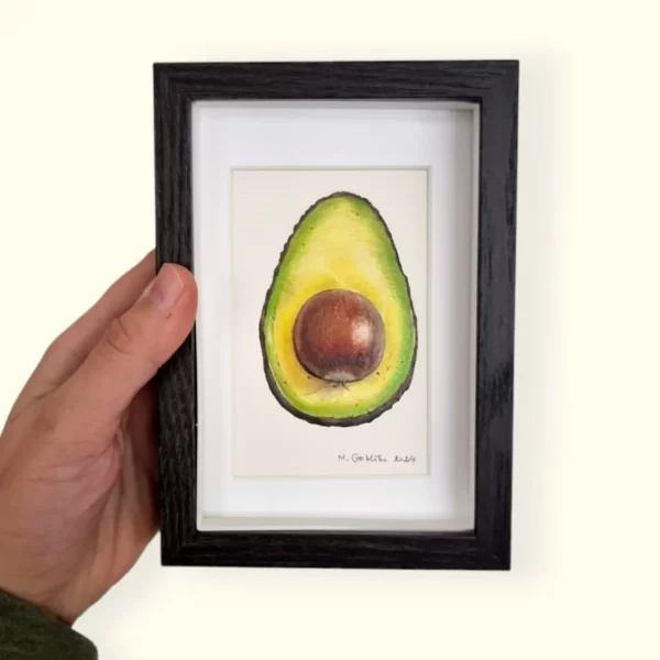 Hand holding a framed avocado drawing