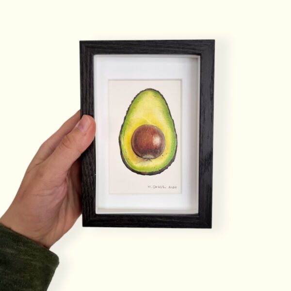 Hand holding a framed delicious avocado miniature drawing